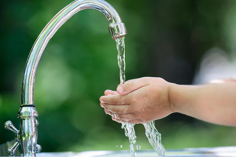 Small hands under running faucet
